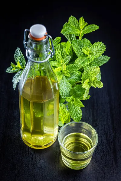 Sweet mint syrup and mint leaves on the black table.
