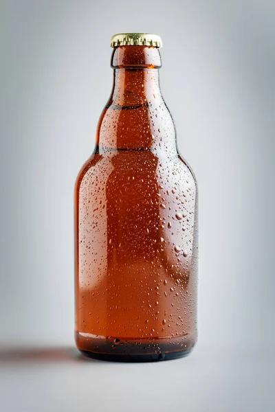 Beer bottle with drops on the gray background.