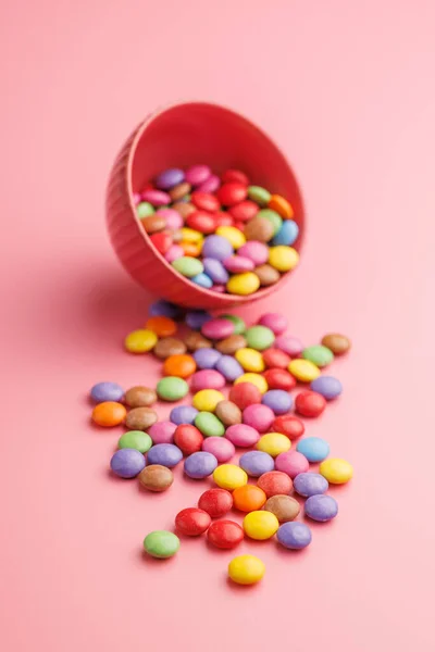 Colorful sweet candies in bowl on the pink background.