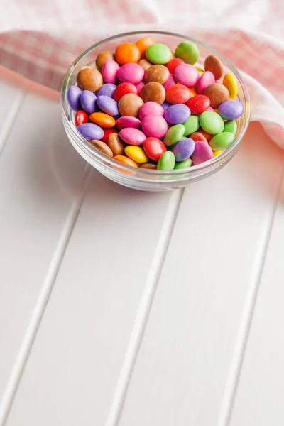 Colorful sweet candies in bowl on the white table.