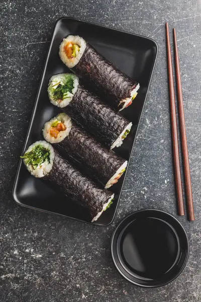 Ein Schwarzer Teller Mit Sushi Stücken Mit Stäbchen Und Einer — Stockfoto