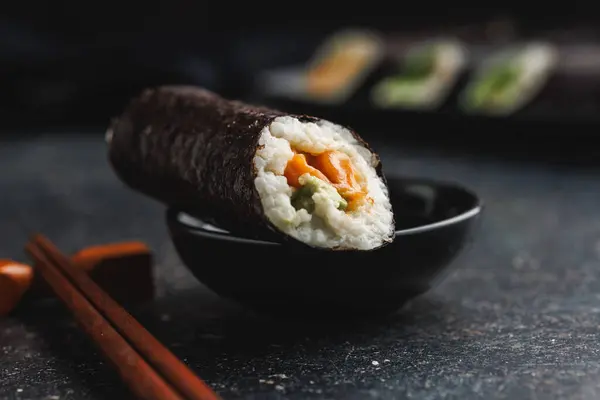 一个带有寿司片和筷子及酱油碗的黑色盘子 寿司展示了各种颜色 质地和填充物 展示了日本料理的艺术性 — 图库照片