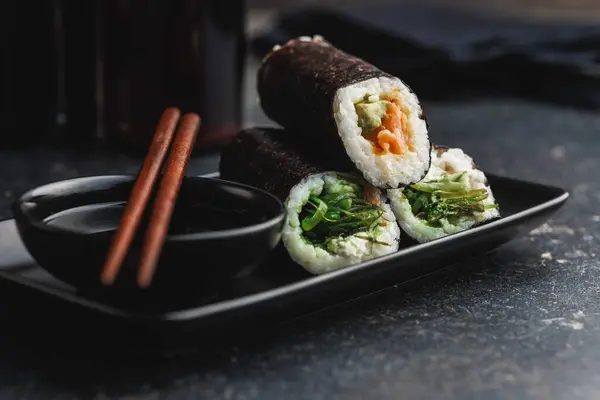 Czarna Płyta Kawałkami Sushi Towarzyszącymi Pałeczkami Miską Sosu Sojowego Sushi — Zdjęcie stockowe