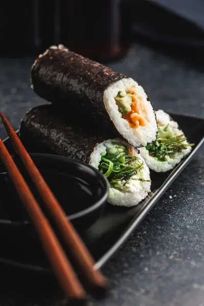 お箸と醤油のボウルを添えた寿司ピース付きのブラックプレート 寿司はさまざまな色 テクスチャ 充填を示し 和食のアーティストリーを紹介しています — ストック写真