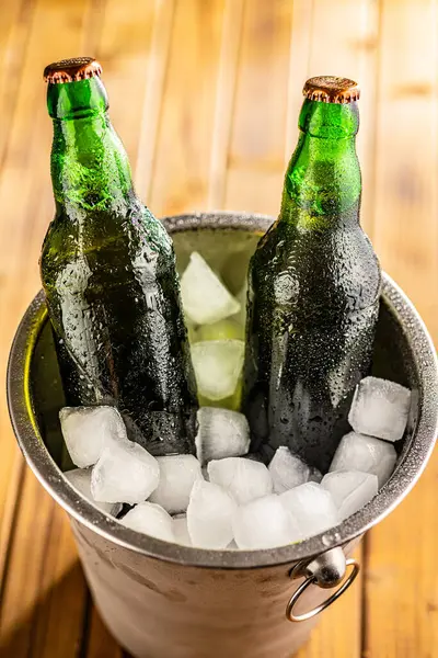 一只金属桶里塞满了冰块 还有两瓶啤酒放在里面 让人觉得很冷 — 图库照片