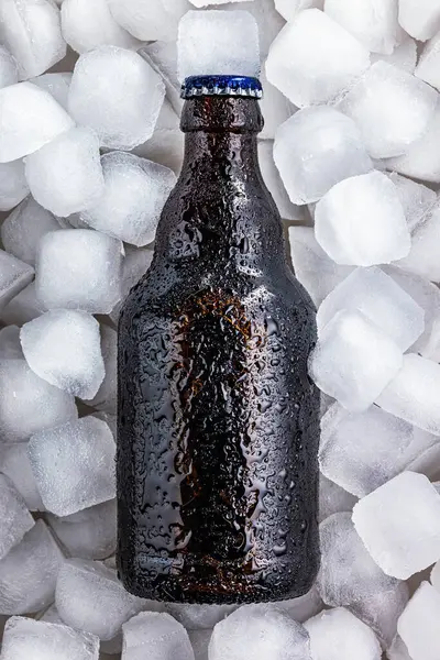 冷たい温度を維持するために表面に形成される凝縮 氷のキューブのリングで冷たいビールの瓶 — ストック写真