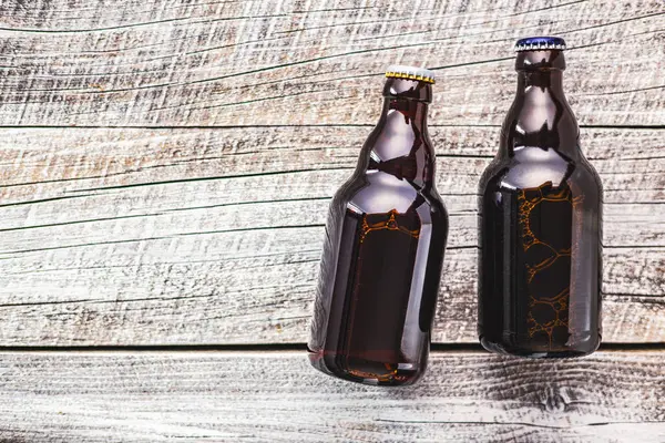 ビールで満たされた2つの茶色のガラスびんは木のテーブルの上にきちんと置かれます ストック画像
