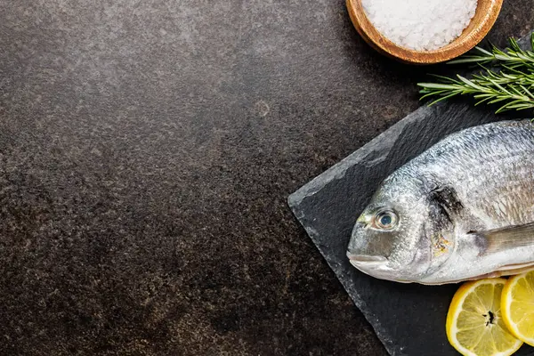 キッチンテーブルのカッティングボード上の新鮮なシーブラム魚 トップビュー ストックフォト