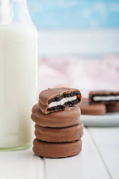 Schokoladenüberzogene Kekse Und Ein Glas Milch Auf Einem Weißen Tisch lizenzfreie Stockbilder