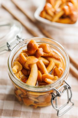 Pickled nameko mushrooms.Traditional japanese mushrooms in jar on a checkered tablecloth. clipart