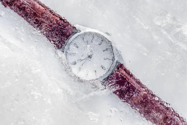 Analogue watch frozen under ice with a brown leather strap. Frozen in time concept