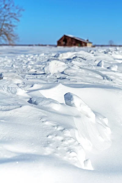 背景にぼやけた田舎の建物と青い空の雪のドリフトに焦点を当てます カナダ ケベック州の冬の風景 — ストック写真