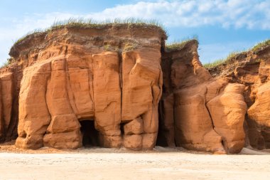 The red cliffs and beach of Havre aux Maisons, on the Gulf of St Lawrence, Magdalen Islands, Canada. Blue sky background. clipart