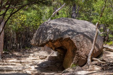 Overhanging boulder next to the stone step pathway of Freycinet National Park, Tasmania, Australia. The oldest of the Tasmanian National Parks and on the East Coast of the Island. clipart