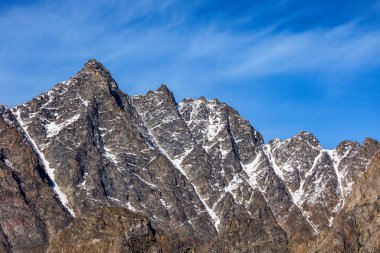 Mountain top and blue sky in Scoresby Sund, Kangertittivaq, East Greenland. The peaks are covered with a sprinkling of light snow. Space for text. clipart