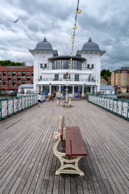 Penarth, Cardiff, UK - 22 June 2024: Looking along Penarth pier towards the 1929 art deco style Pavilion with the town behind.Vale of Glamorgan, Wales. clipart