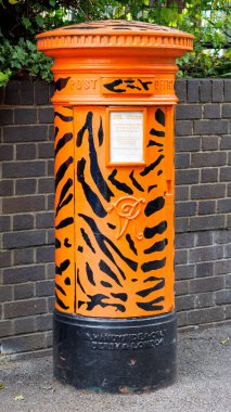 London, UK - 26 April 2024: Traditional Victorian postbox in London Zoo, Regents Park. This is painted with a tiger skin design, and is used to collect charitable donations to help fund the zoo. clipart