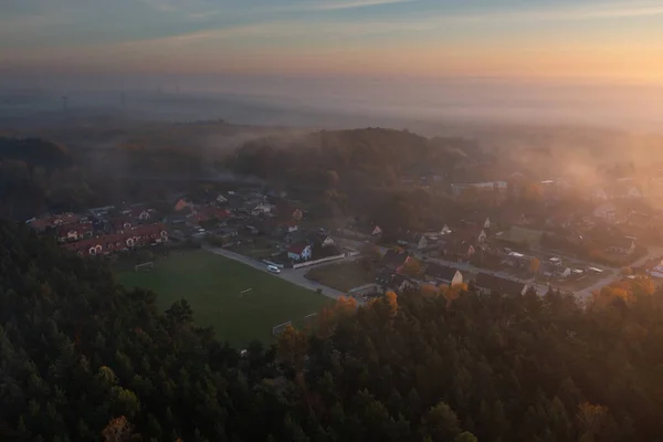 Morning fog over the forest and buildings in northern Poland