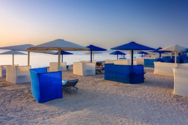 Şemsiyeli güneş pansiyonları güneş doğarken Marsa Alam plajında, Mısır