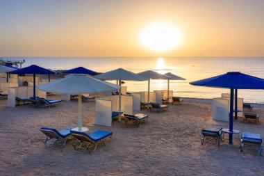 Şemsiyeli güneş pansiyonları güneş doğarken Marsa Alam plajında, Mısır
