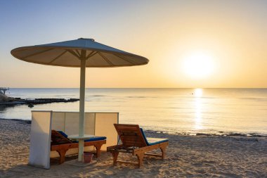Şemsiyeli güneş pansiyonları güneş doğarken Marsa Alam plajında, Mısır