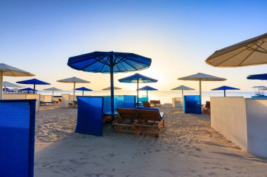 Şemsiyeli güneş pansiyonları güneş doğarken Marsa Alam plajında, Mısır