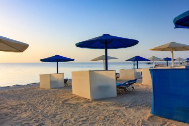 Şemsiyeli güneş pansiyonları güneş doğarken Marsa Alam plajında, Mısır