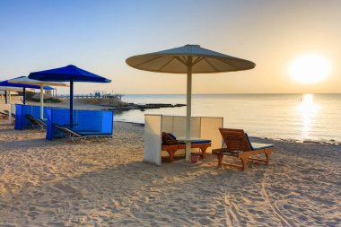 Şemsiyeli güneş pansiyonları güneş doğarken Marsa Alam plajında, Mısır