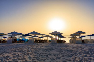 Şemsiyeli güneş pansiyonları güneş doğarken Marsa Alam plajında, Mısır