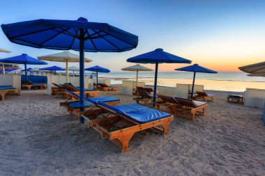 Şemsiyeli güneş pansiyonları güneş doğarken Marsa Alam plajında, Mısır