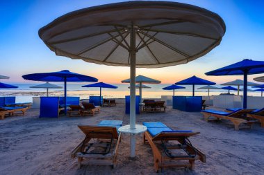 Şemsiyeli güneş pansiyonları güneş doğarken Marsa Alam plajında, Mısır