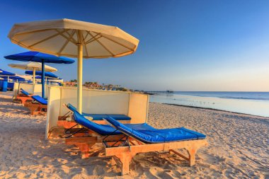 Şemsiyeli güneş pansiyonları güneş doğarken Marsa Alam plajında, Mısır