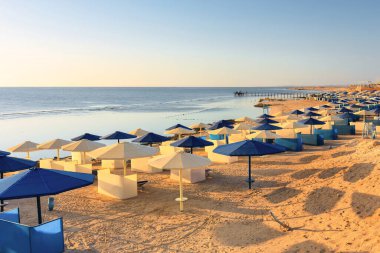 Şemsiyeli güneş pansiyonları güneş doğarken Marsa Alam plajında, Mısır