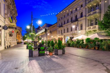 Lodz, Polonya - 24 Ağustos 2023: Lodz şehrindeki Piotrkowska Caddesi 'nin şafak vakti en uzun ticari caddelerden biri olan 4.2 km uzunluğundaki güzel mimarisi. Polonya