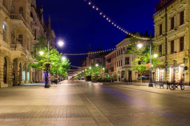Lodz, Polonya - 24 Ağustos 2023: Lodz şehrindeki Piotrkowska Caddesi 'nin şafak vakti en uzun ticari caddelerden biri olan 4.2 km uzunluğundaki güzel mimarisi. Polonya