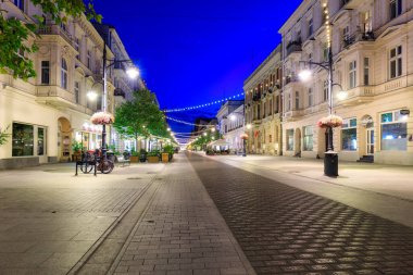 Lodz, Polonya - 24 Ağustos 2023: Lodz şehrindeki Piotrkowska Caddesi 'nin şafak vakti en uzun ticari caddelerden biri olan 4.2 km uzunluğundaki güzel mimarisi. Polonya