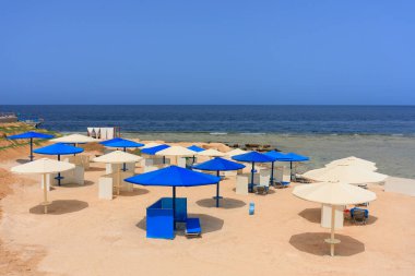 Şemsiyeli güneş pansiyonları güneş doğarken Marsa Alam plajında, Mısır