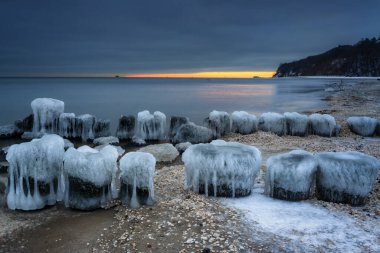 Gün batımında Babie Doly 'de donmuş Baltık Denizi plajı, Gdynia. Polonya