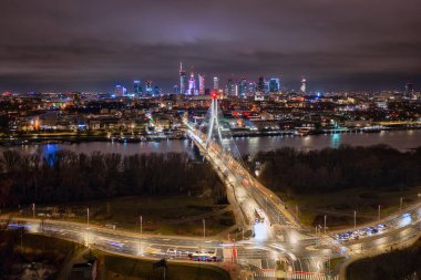 Vistula Nehri üzerindeki Swietokrzyski Köprüsü geceleri Varşova 'nın merkezini panoramik olarak görüyor. Polonya