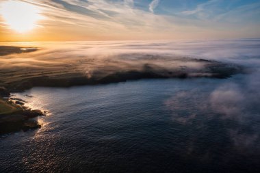 Kilkee, Co. Clare 'in kayalık sahillerinde puslu bir gün doğumu. İrlanda