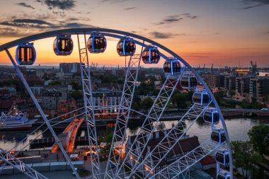 Günbatımında parlayan dönme dolaba sahip ana şehir Gdansk, Polonya.