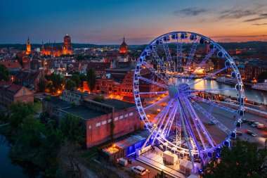 Günbatımında parlayan dönme dolaba sahip ana şehir Gdansk, Polonya.