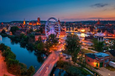 Günbatımında parlayan dönme dolaba sahip ana şehir Gdansk, Polonya.