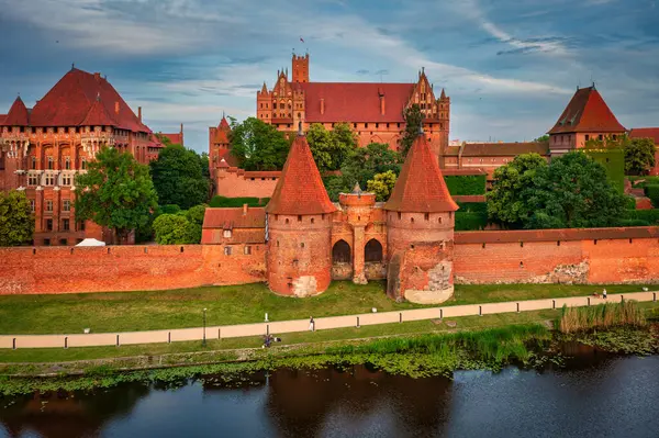 stock image Castle of theTeutonic Order in Malbork by the Nogat river at sunset.