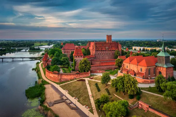 stock image Castle of theTeutonic Order in Malbork by the Nogat river at sunset.