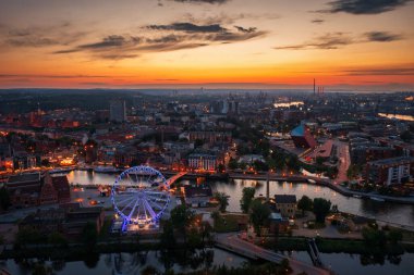 Günbatımında parlayan dönme dolaba sahip ana şehir Gdansk, Polonya.
