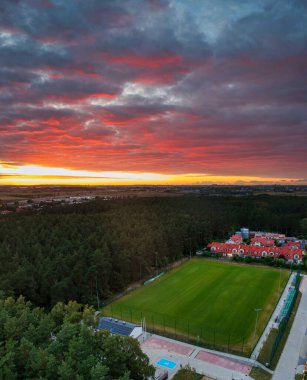 Gün batımında ormanın yanındaki futbol sahasının hava manzarası.