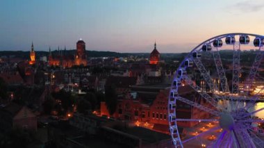 Günbatımında parlayan dönme dolaba sahip ana şehir Gdansk, Polonya.