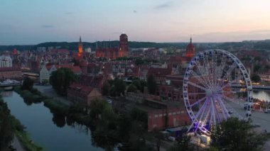 Günbatımında parlayan dönme dolaba sahip ana şehir Gdansk, Polonya.