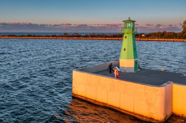 Günbatımında Nowy Limanı 'nın batı dalgakıranında yeşil deniz feneri, Gdansk.